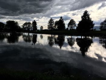 Silhouette trees by lake against sky during sunset
