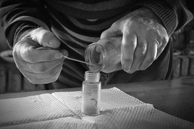 Close-up of man holding glass bottle on table