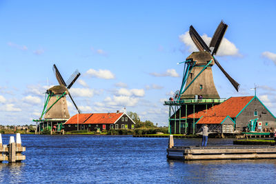 Traditional windmill by water against sky