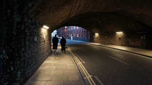 Rear view of people walking in tunnel