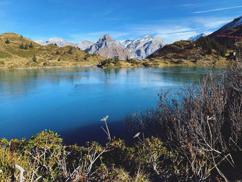Scenic view of lake and mountains against blue sky