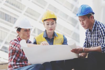 Architects discussing over blueprint while working at construction site