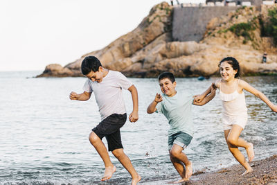 Three funny kids running on the beach