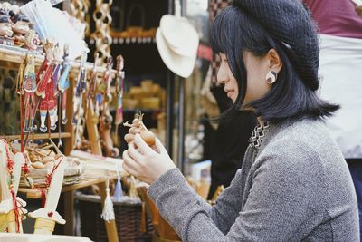 Side view of woman holding umbrella at store