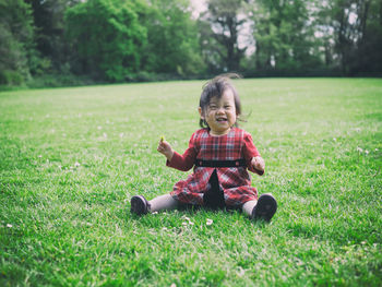 Full length of happy girl sitting on grass