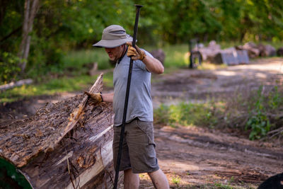 Full length of man working with log in forest