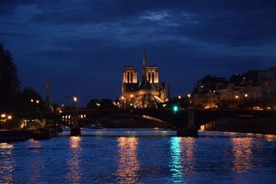 Illuminated bridge over river against sky in city at night