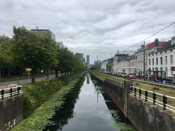 Canal amidst buildings in city against sky