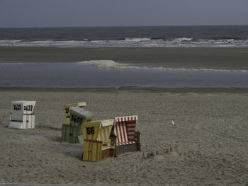 Hooded chairs on beach against sky