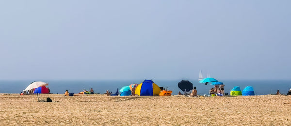 Group of people on beach against clear sky