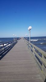 Pier over sea against clear blue sky