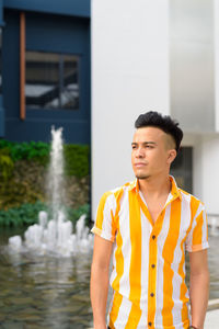 Portrait of young man standing against water