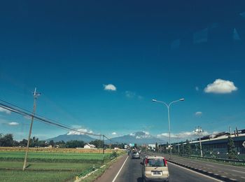 Vehicles on road against blue sky