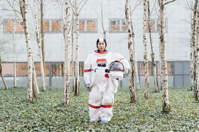 Female astronaut holding space helmet while standing in garden