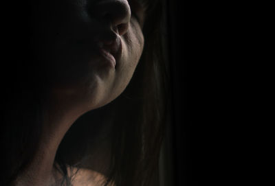 Close-up of woman against black background