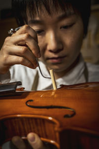 Young chinese violin maker at work in her workshop