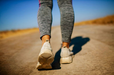 Sport legs in white sneakers walking on road