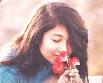 Close-up of teenage girl smelling red roses at park