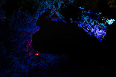 Illuminated rock formation in sea at night