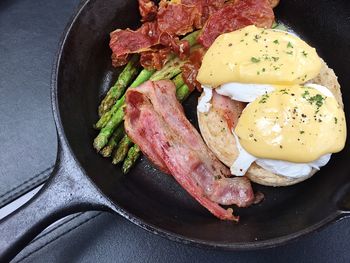 High angle view of eggs benedict with meat and asparagus in skillet