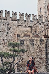 Woman sitting on railing against historic building