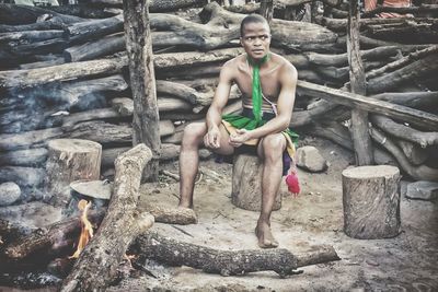 Portrait of young man sitting on wood