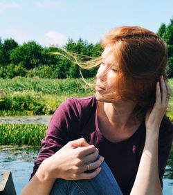 Close-up of woman sitting by lake during sunny day