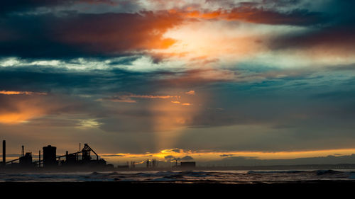 Scenic view of sea against dramatic sky during sunset