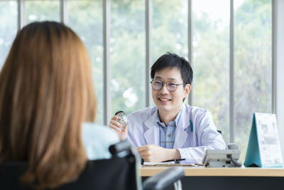 Portrait of young woman using mobile phone at office