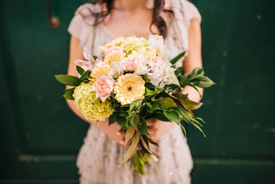 Midsection of bride holding flower bouquet