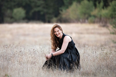 Portrait of smiling young woman sitting on land