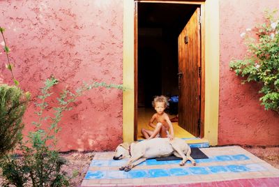 Shirtless boy sitting by dog at home