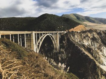 Arch bridge over mountains against sky