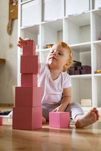 Cute girl looking away while sitting in box at home