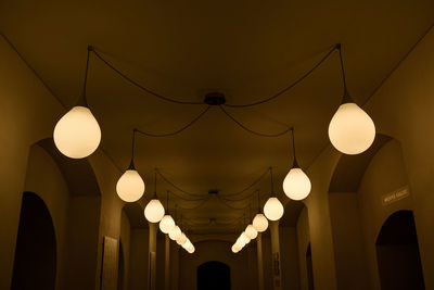 Low angle view of illuminated light bulbs hanging from ceiling