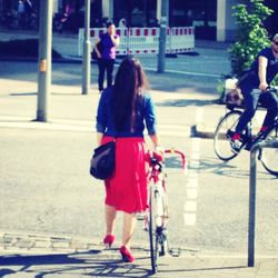 Rear view of woman standing on road in city