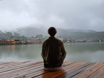 Rear view of woman looking at lake against sky