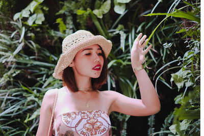 Thoughtful young woman standing by plants