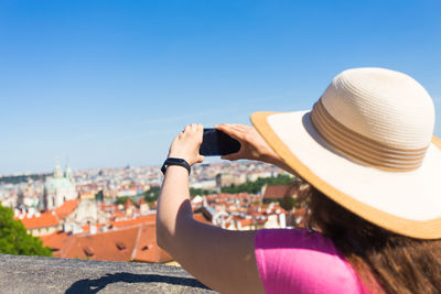 Rear view of woman using mobile phone against sky