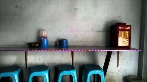 Plastic stools under table by wall at cafe
