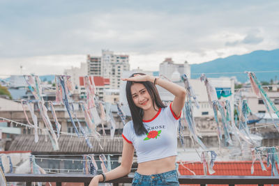 Full length of young woman standing against cityscape