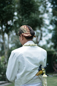 Rear view of man wearing mask against trees