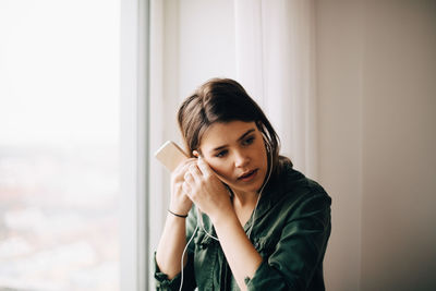 Portrait of beautiful young woman holding window