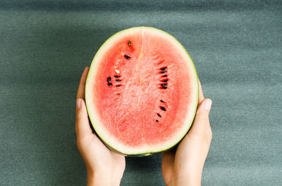 Cropped hands of person holding watermelon on table