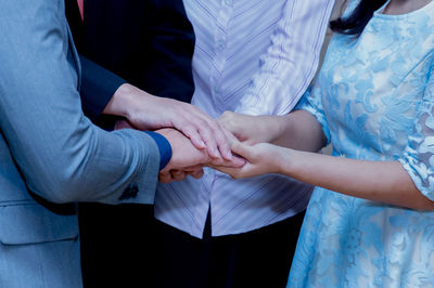 Midsection of people stacking hands