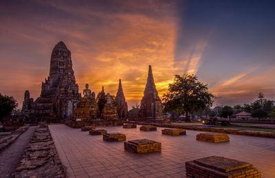 Temple by building against sky during sunset