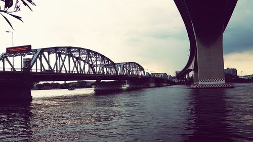 Bridge over river in city against sky