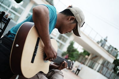 Tilt shot of street musician playing guitar in city
