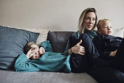 Woman spending leisure time with sons on sofa at home