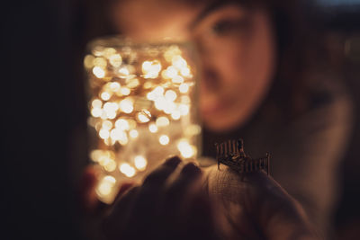 Close-up of woman holding illuminated lighting equipment in jar
